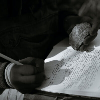 Man Holding Rock and Taking Notes by Plato Terentev
